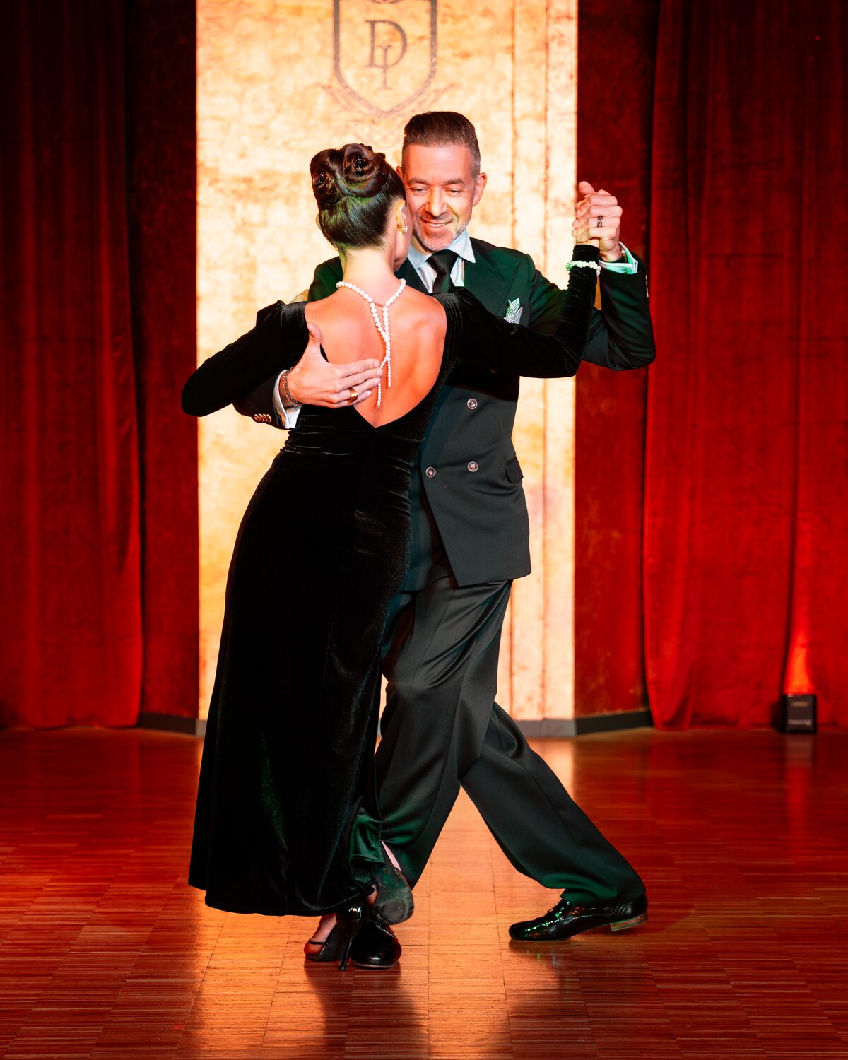 Tanzpaar in eleganter Abendgarderobe bei einer Tango-Argentino-Show vor dem DANCEIMPERIAL-Wappen, DANCEIMPERIAL Regensburg